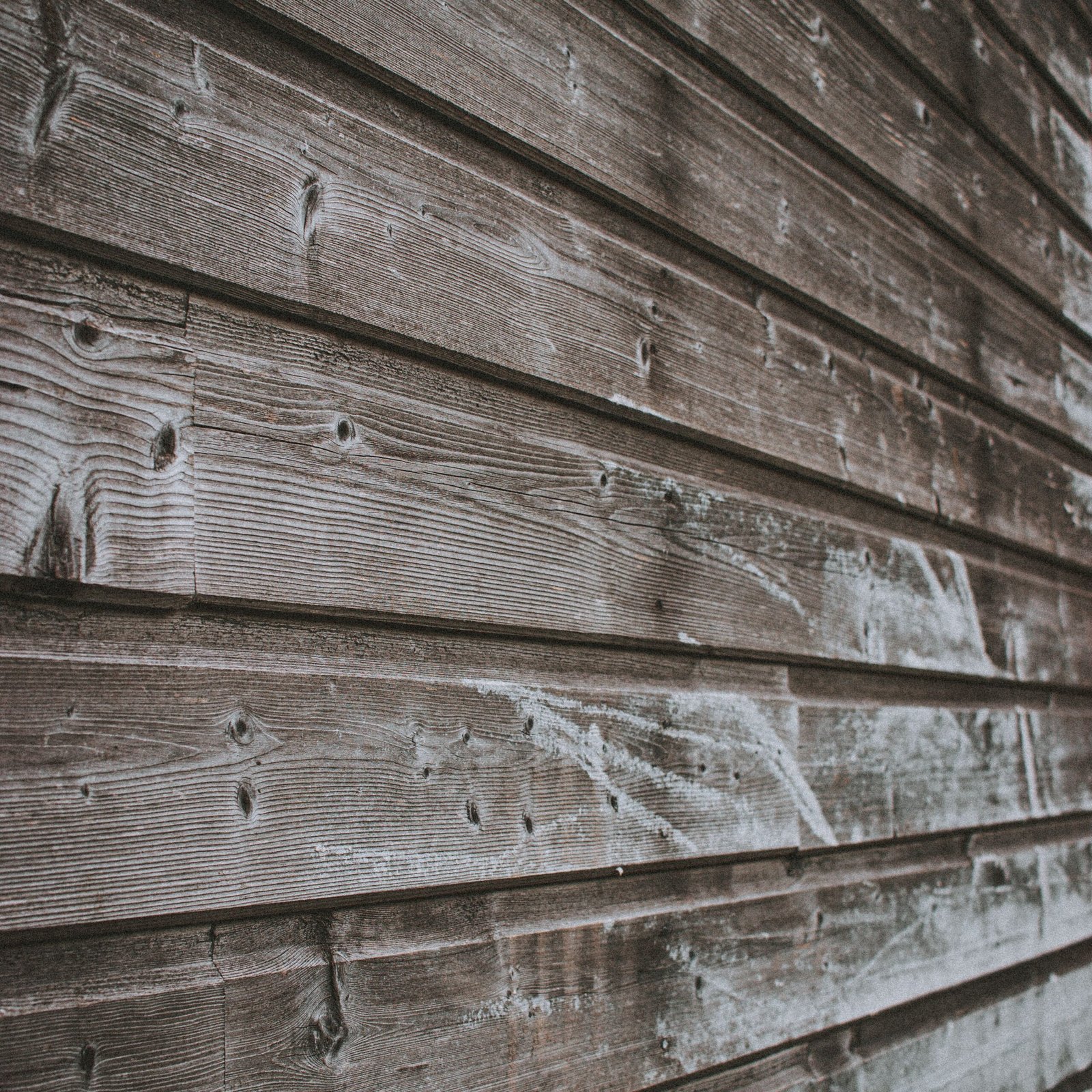 Weathered wall of aged lumber house covered with stains of dirt in countryside